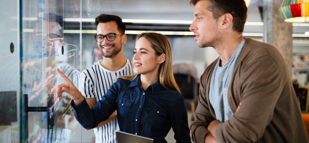 employees pointing at board looking happy
