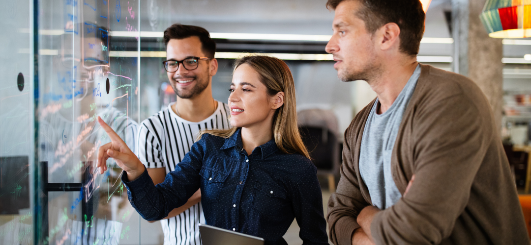 employees pointing at board looking happy