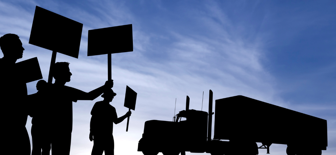 people striking with a vehicle in the background