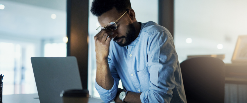 man holding his face over laptop
